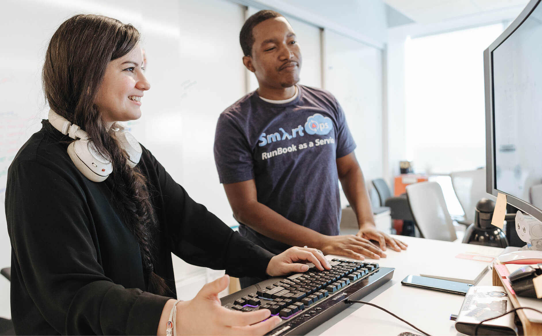 Two Capital One Tech associates standing at a computer smiling and collaborating